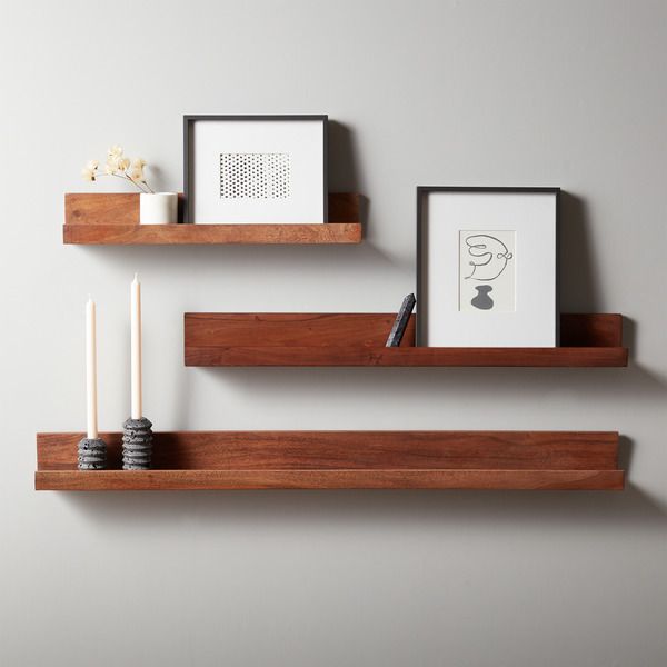 three wooden floating shelves with picture frames and candles